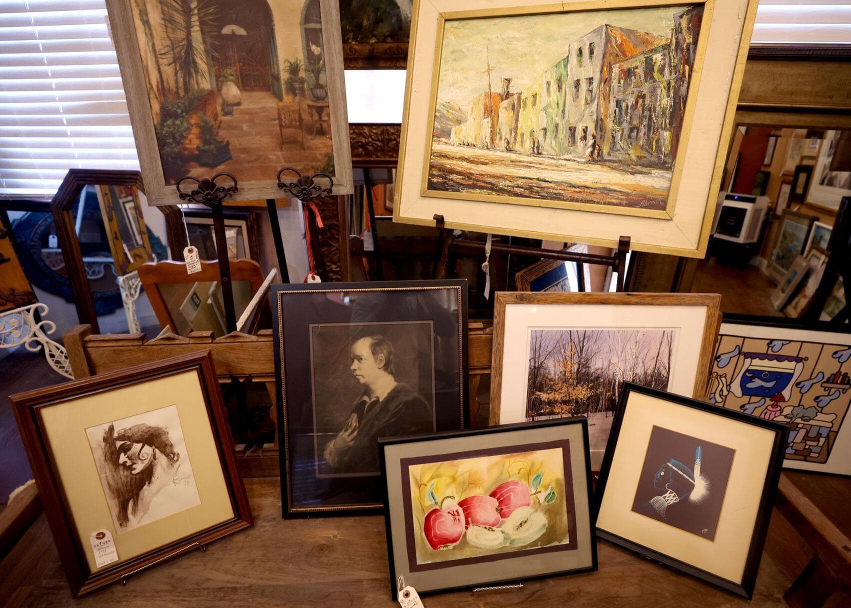 A selection of framed paintings and prints on display at Gather a Vintage Market, highlighting the variety of vintage artwork available to buyers.