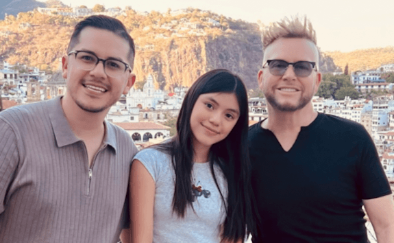 A family photo shows a reality TV star (left), his daughter (center) and his partner (right). The star has requested a medical emergency travel visa after his daughter was airlifted to a Phoenix hospital.