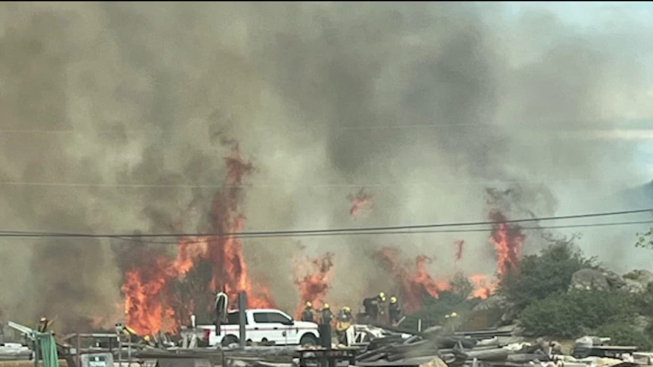 Firefighters and vehicles work amid heavy flames and thick smoke as the Mina Fire burns near Yarnell on July 4, prompting evacuations and destroying outbuildings.