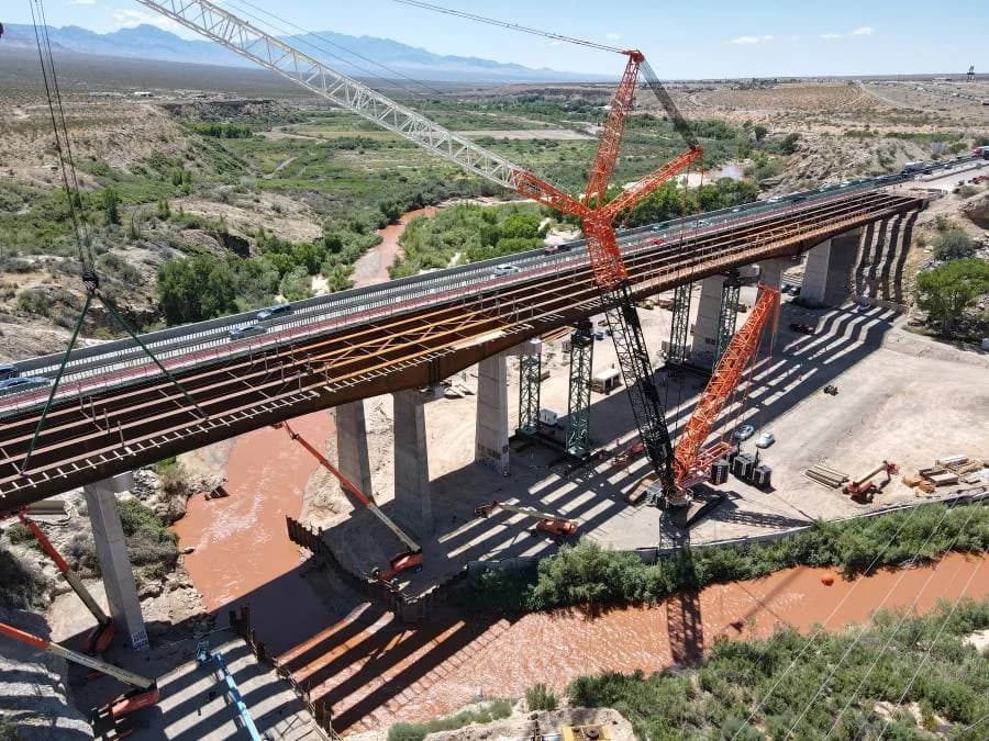 Cranes and crews lift and install a bridge span over a river in the Southwest — an infrastructure project representative of the community-benefit and innovation winners featured in ENR’s Best Projects.
