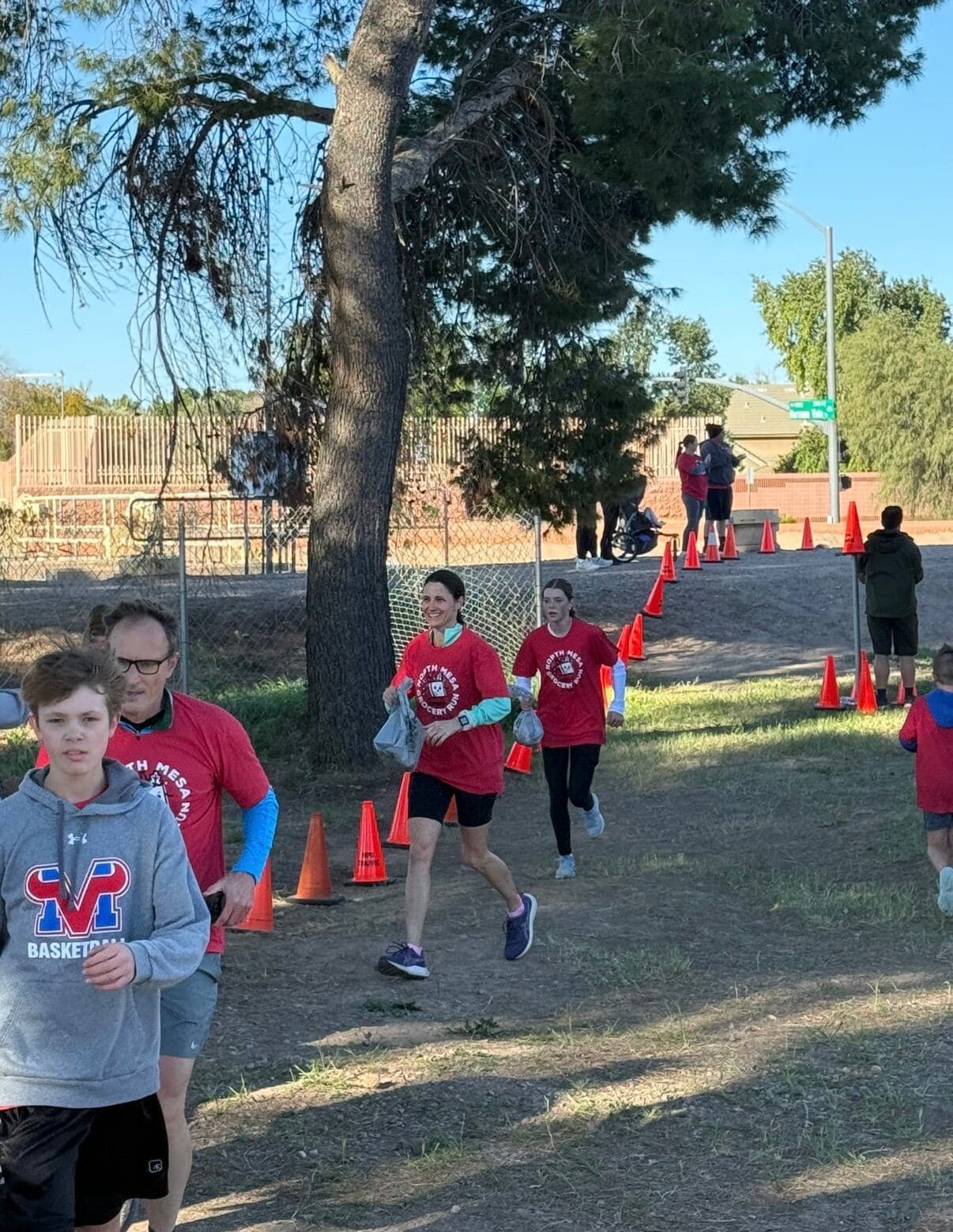 Participants in red event shirts carry bags of donated food along the 5K route, collecting items for local pantries.