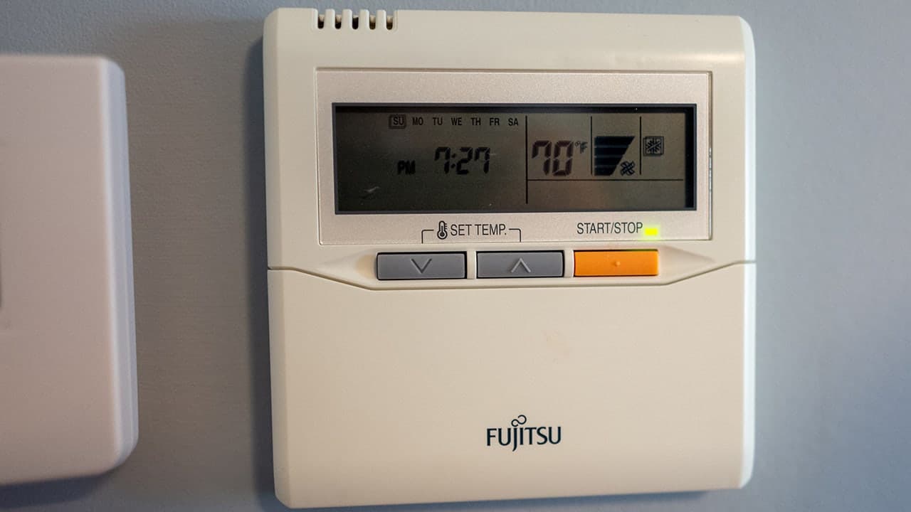 Wall-mounted Fujitsu thermostat showing 70°F — an example of the settings homeowners can adjust to trim A/C costs during extreme Phoenix heat.