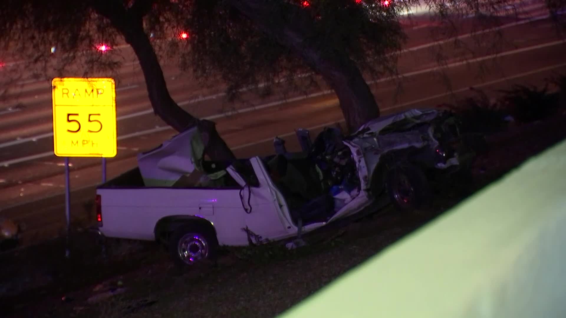 Severely damaged pickup resting by trees and a ramp sign after the crash in Phoenix — one of the vehicles involved in the overnight collision that sent three people to the hospital.