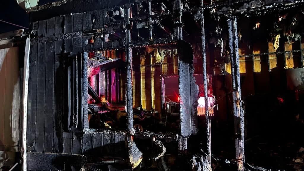 Charred exterior and exposed framing of a structure after an Arizona fire; DFFM says strategic patrols and staged crews helped stop two wildfires.