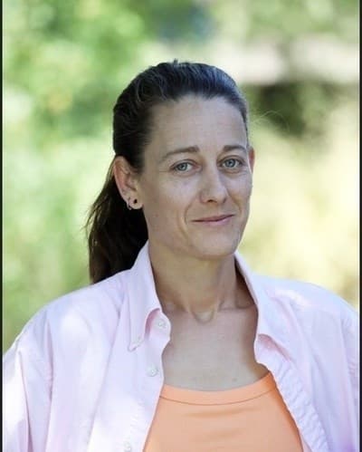 Portrait published with the obituary — a head-and-shoulders photo of a woman outdoors, wearing a light pink shirt over an orange top.