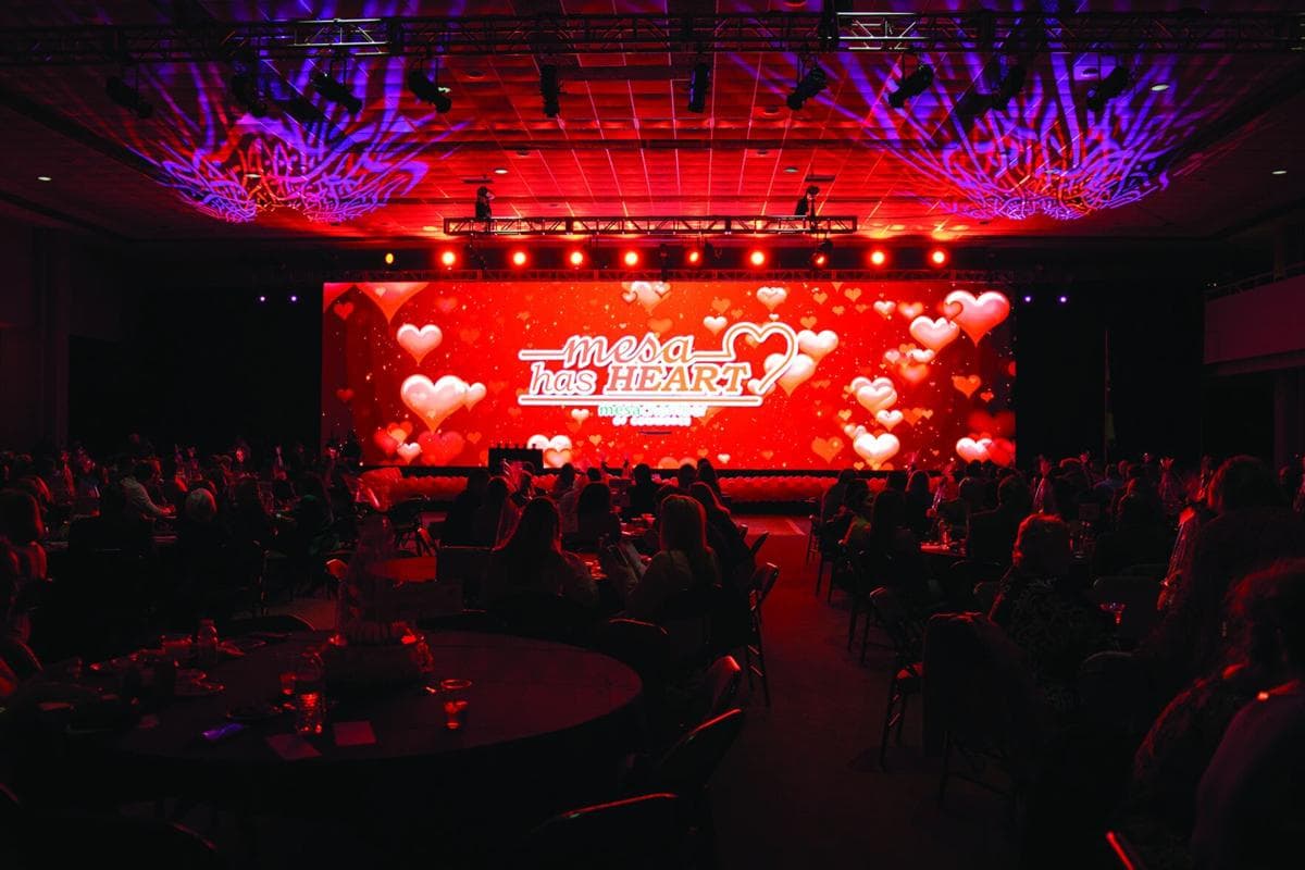 Audience members watch the 'Mesa Has Heart' stage presentation during the Mesa Chamber awards event, the auditorium lit in red for the gala.