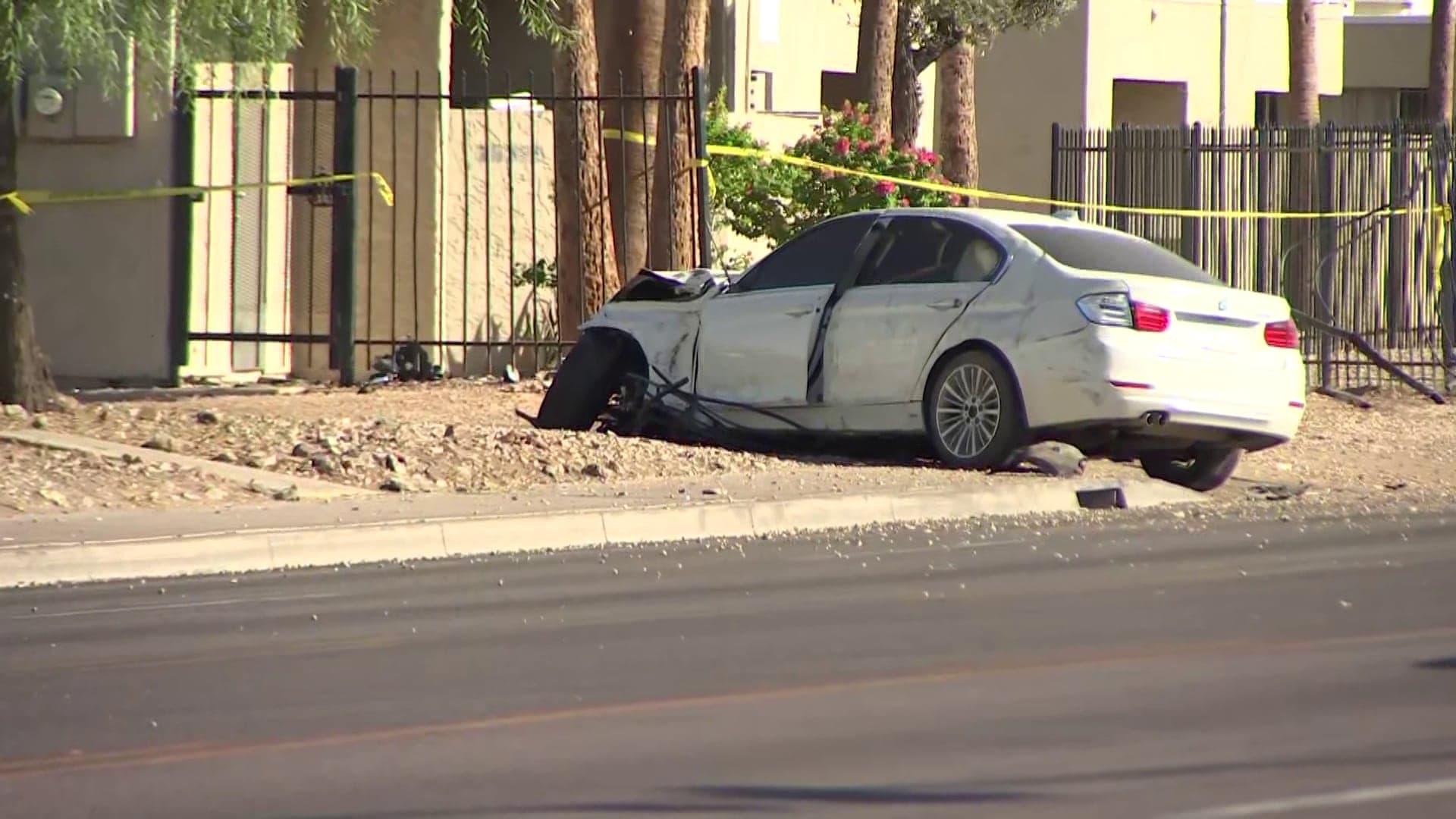 Wrecked white sedan on a west Phoenix roadway, cordoned off with police tape after a hit-and-run collision investigators say occurred on Camelback Road.